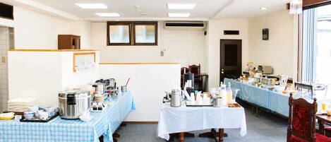 A hotel room with a checkered tablecloth, a coffee station, and a dining area with a blue tablecloth.