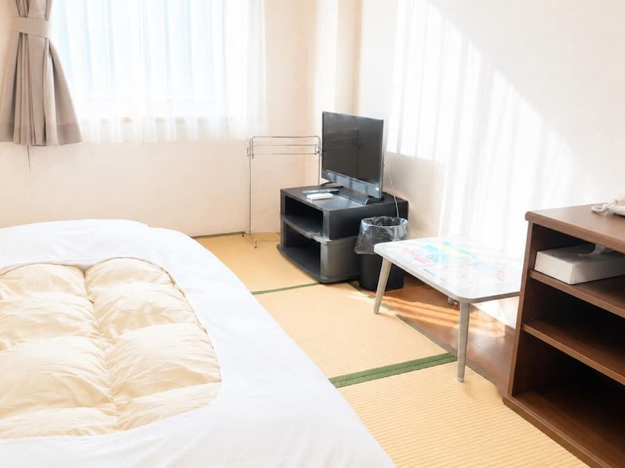 Une chambre d’hôtel avec un lit, un bureau avec un ordinateur, une chaise et une petite table sur laquelle est posée une carte.