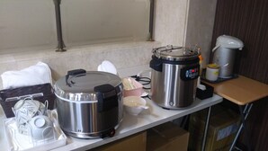 A kitchen with stainless steel appliances, a white countertop, and a window with curtains. - Hotel Hitachi Hills (Hitachi)