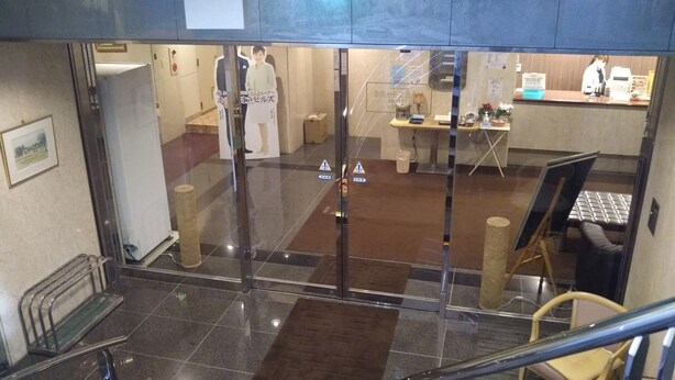 A hotel lobby with a reception desk, a seating area, and a staircase. - Hotel Hitachi Hills (Hitachi)