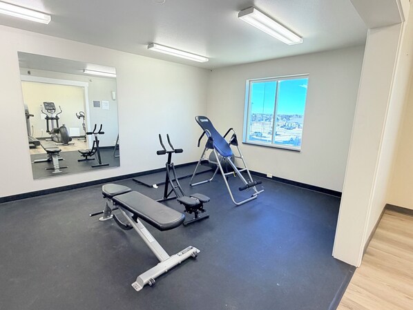 A gym with exercise equipment, a large mirror, and a window with a view.