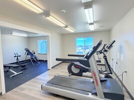 Un gimnasio moderno con equipo de cardio, un espejo grande y amplias ventanas con vistas.