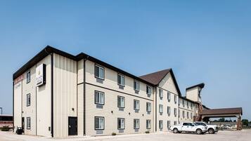 A multi-story hotel with a flat roof and a covered parking area.
