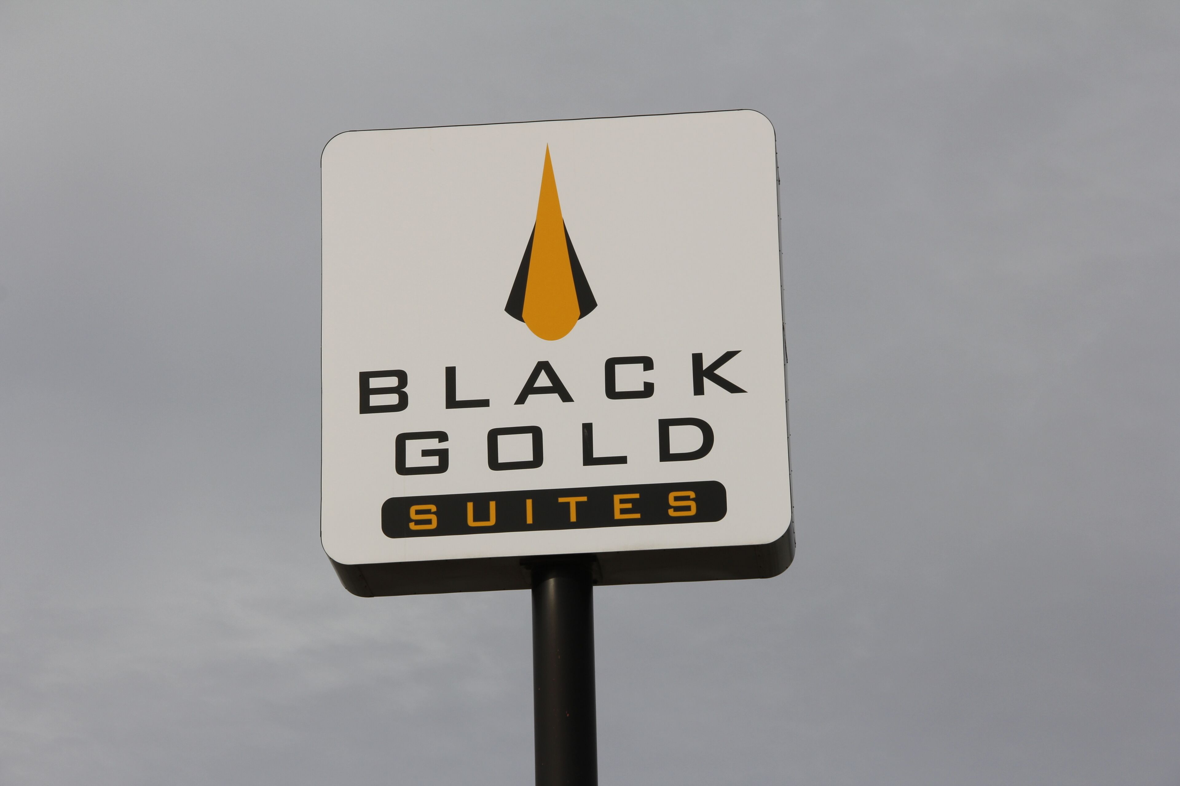 Un cartell per a Black Gold Suites amb un logotip estilizado sobre el text.
