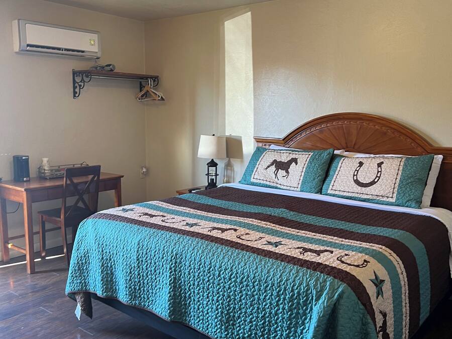A neatly arranged bedroom with a bed, a desk, and a chair.