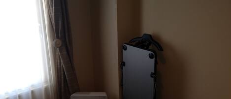 Um quarto com uma mala, uma caixa branca pequena e uma janela com cortinas.