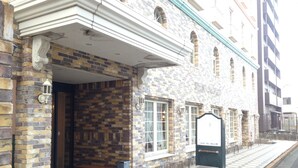 Un edificio con fachada de ladrillo, entrada de azulejos y un cartel.