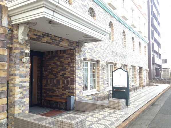 Un bâtiment à la façade en briques, avec un porche carrelé et une enseigne.