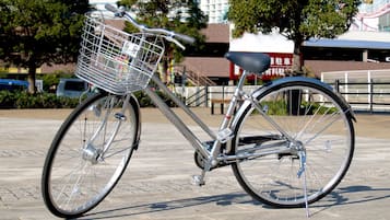 Una bicicleta estática con una cesta delantera, estacionada sobre una superficie pavimentada.