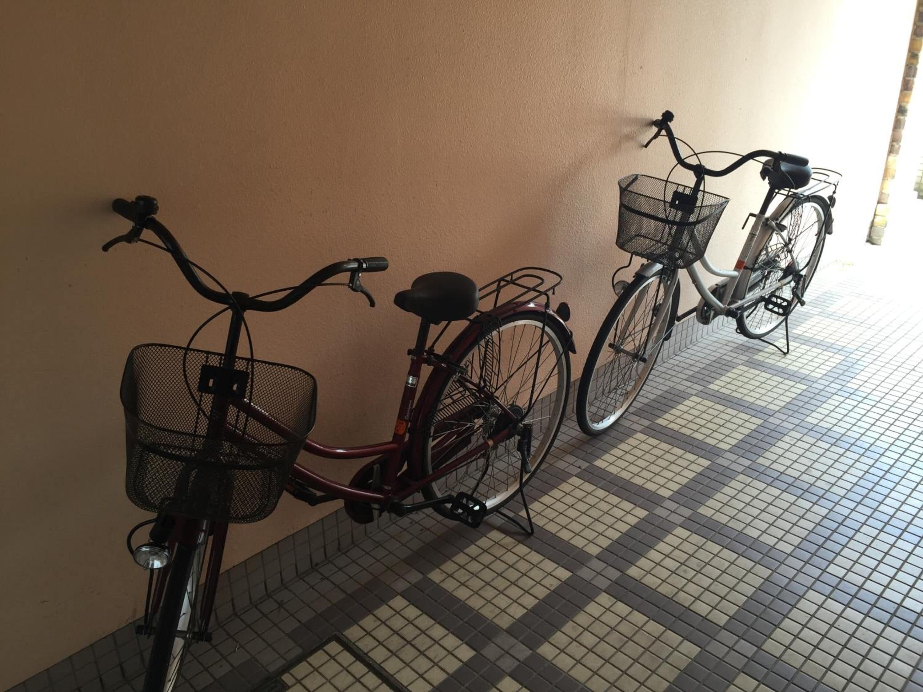 Two bicycles parked against a wall with a tiled floor.