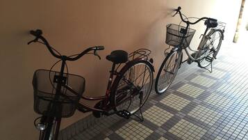 Two bicycles parked against a wall with a tiled floor.