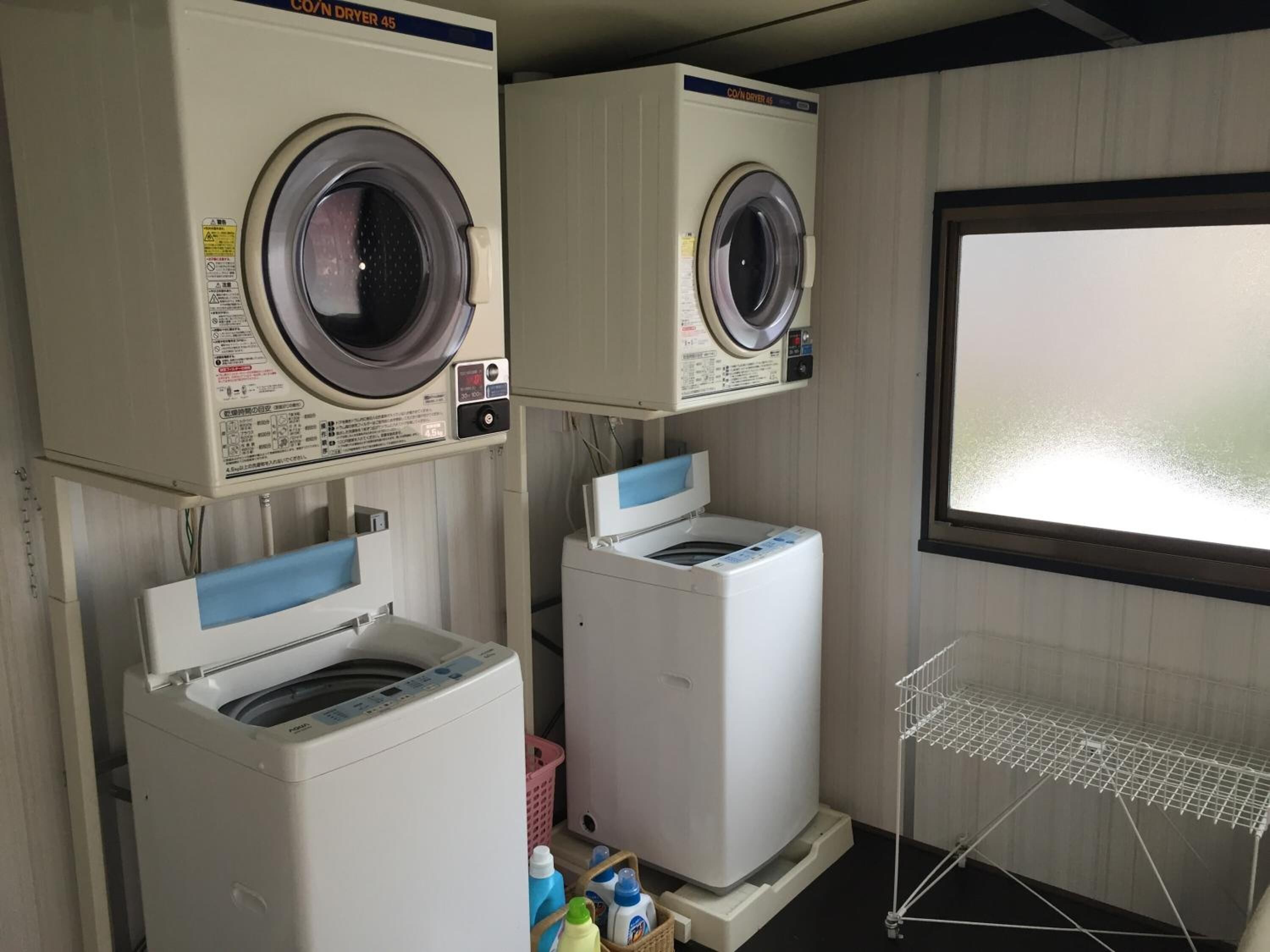 Une buanderie équipée de deux machines à laver à chargement frontal, d’un sèche-linge et d’un étendoir métallique.