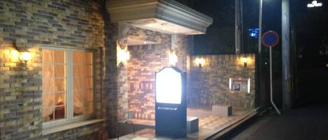 A building with a brick facade, a covered entrance, and a no parking sign.