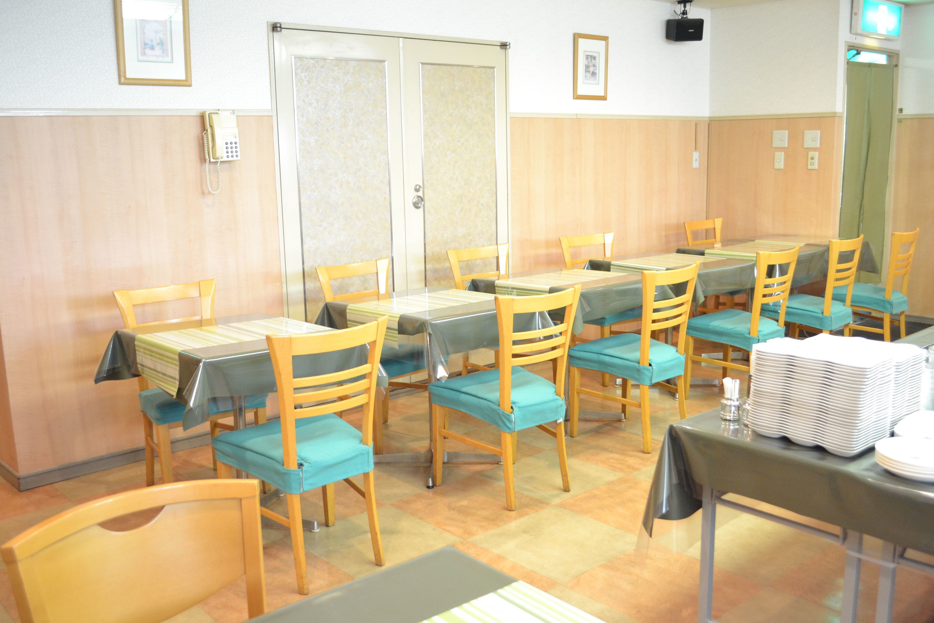 A conference room with multiple tables and chairs, a telephone, and a projector mounted on the wall.