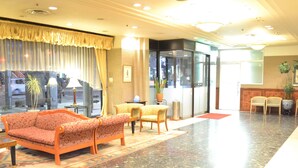 Eine Lobby mit einer Couch, Stühlen, einem Tisch und einer Zimmerpflanze.