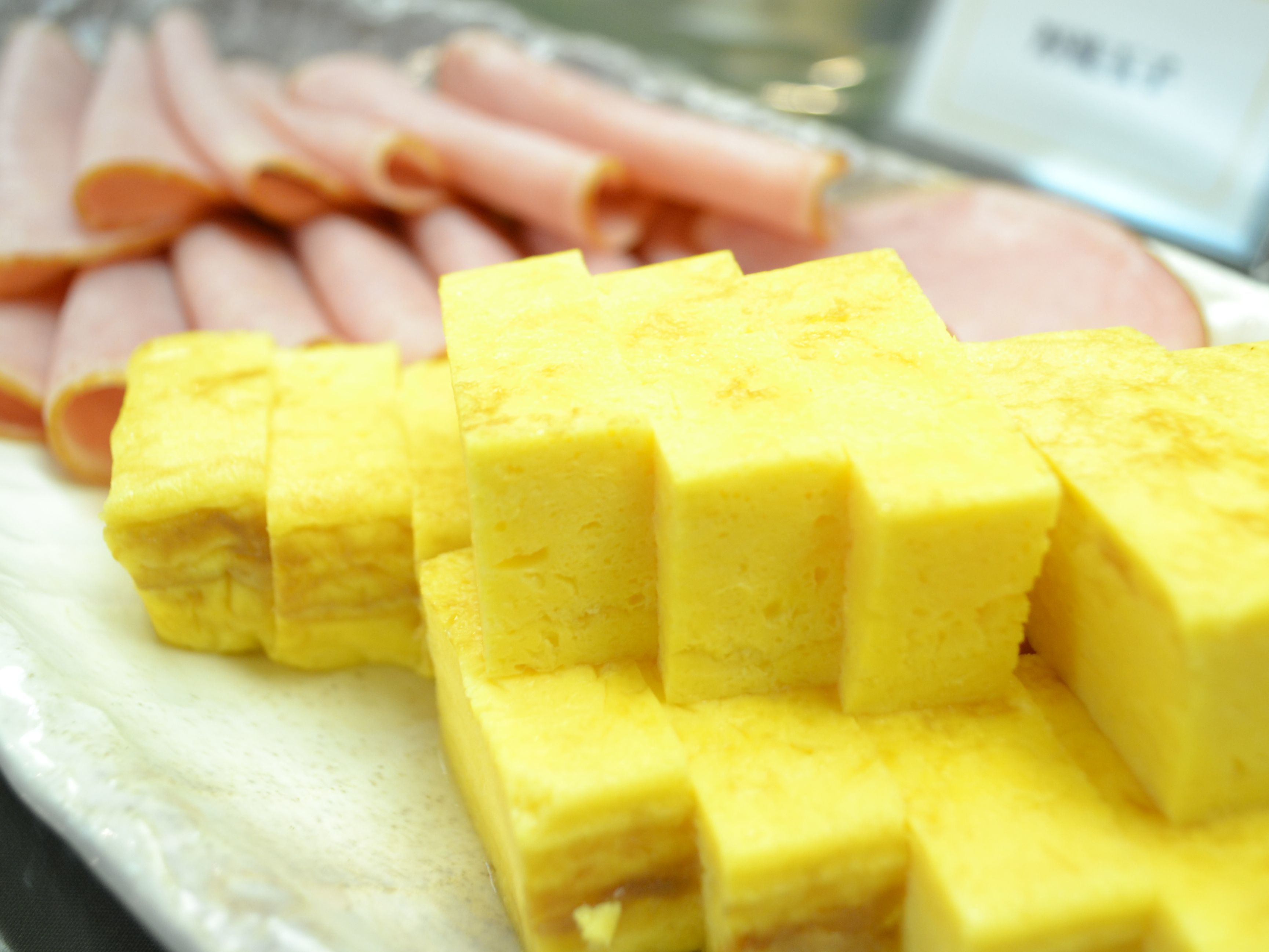 A plate with yellow cubes and sliced ham.