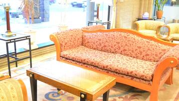 A room with a sofa, a coffee table, and a chair. There is a window with a view of the street outside.