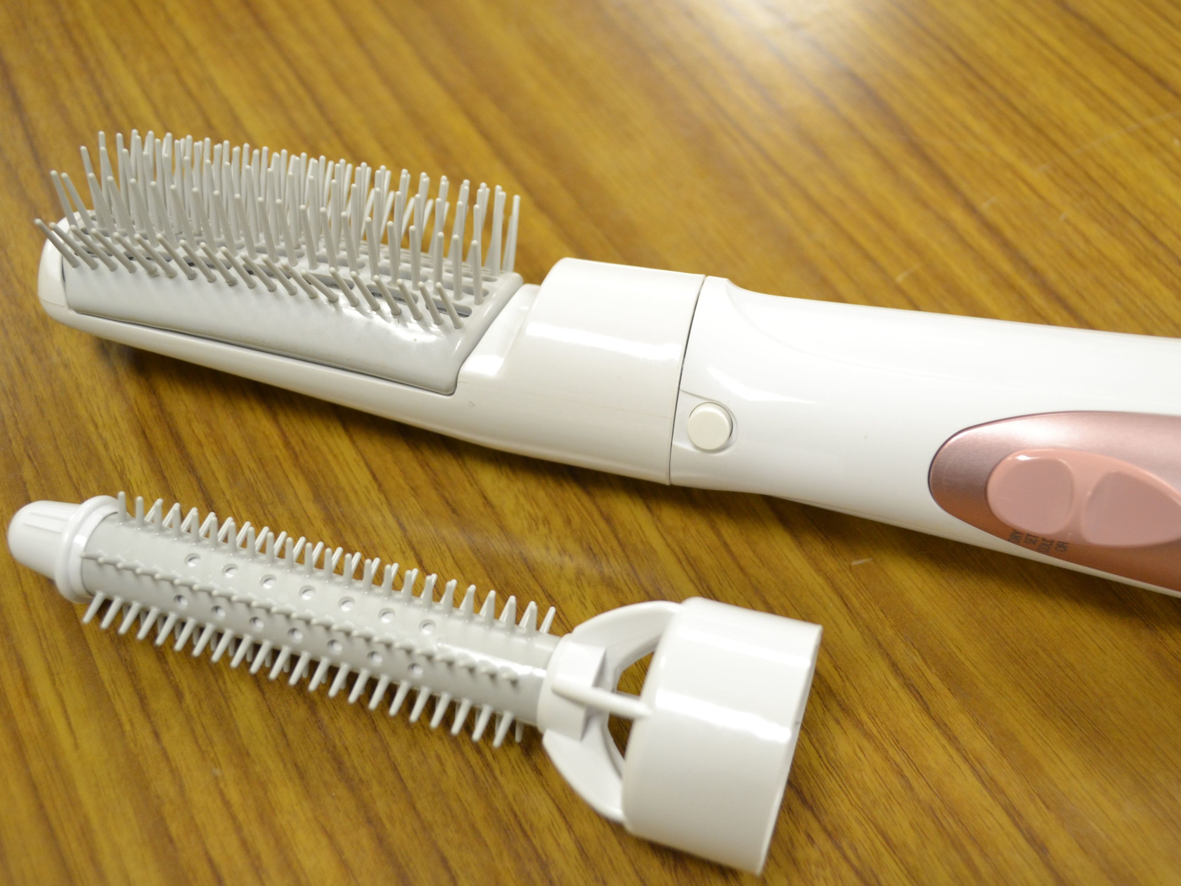 Two white electric toothbrushes with pink handles on a wooden surface.