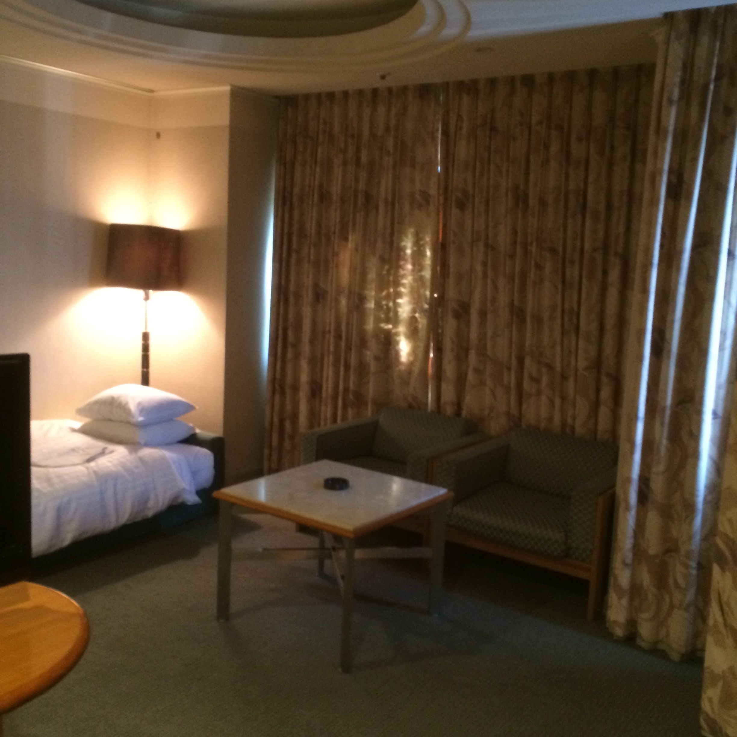 A hotel room with a bed, a small table, a sofa, and a lamp.