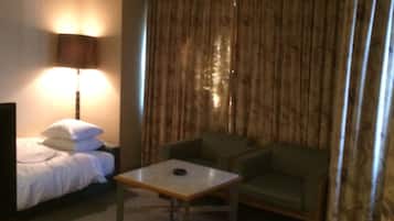 A hotel room with a bed, a small table, a sofa, and a lamp.