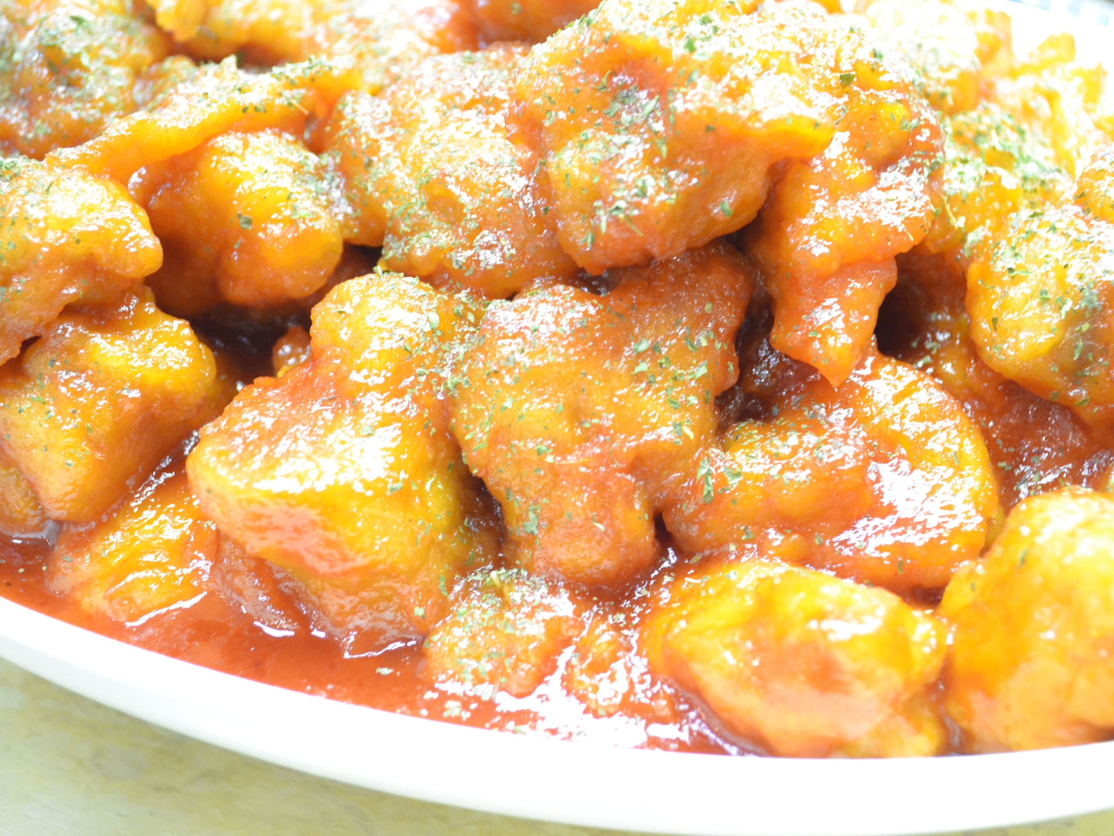 A dish of food with chunks of meat and a tomato-based sauce.