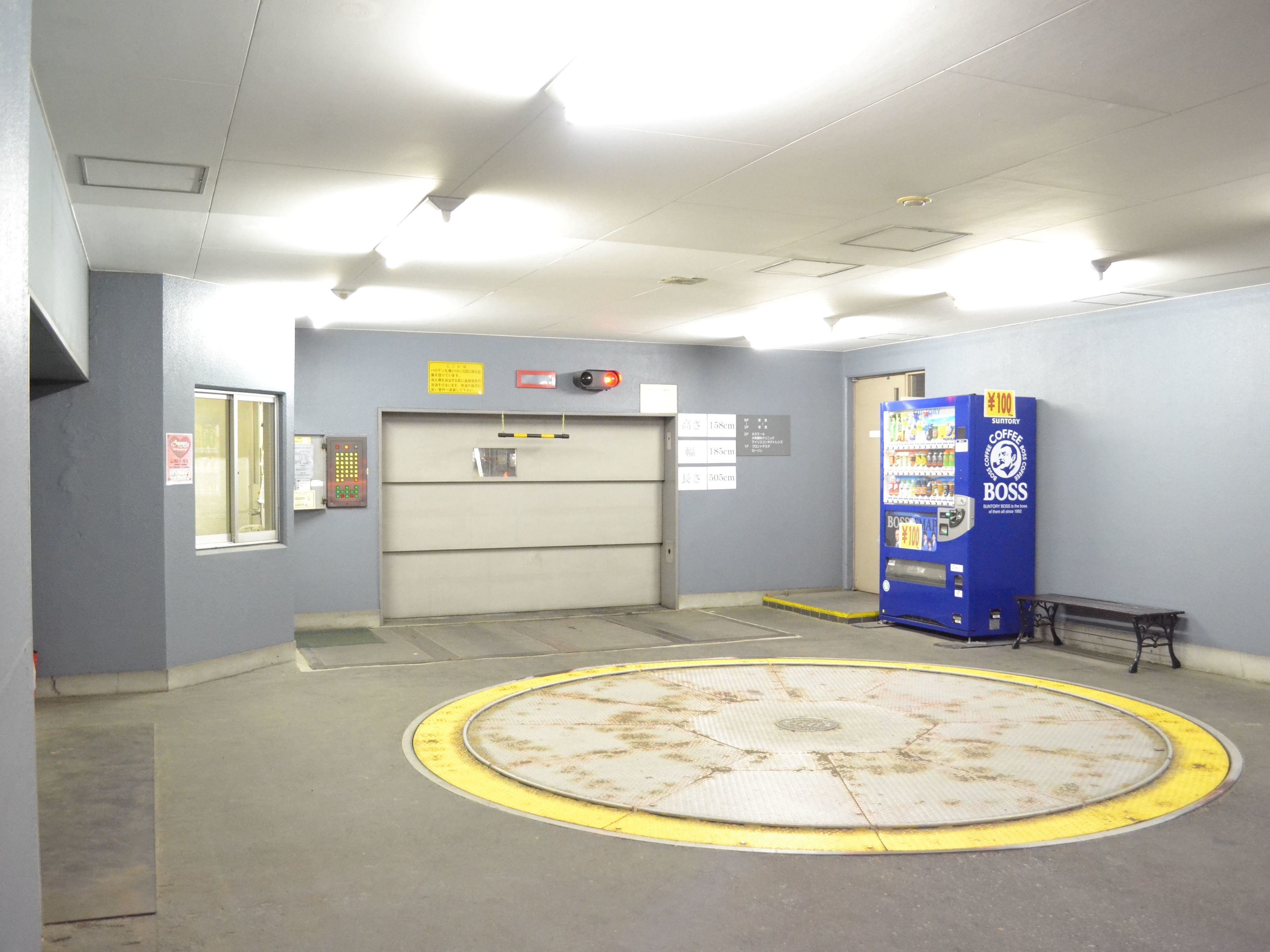 A hallway with a blue vending machine, a fire alarm, and a door with a height restriction sign.