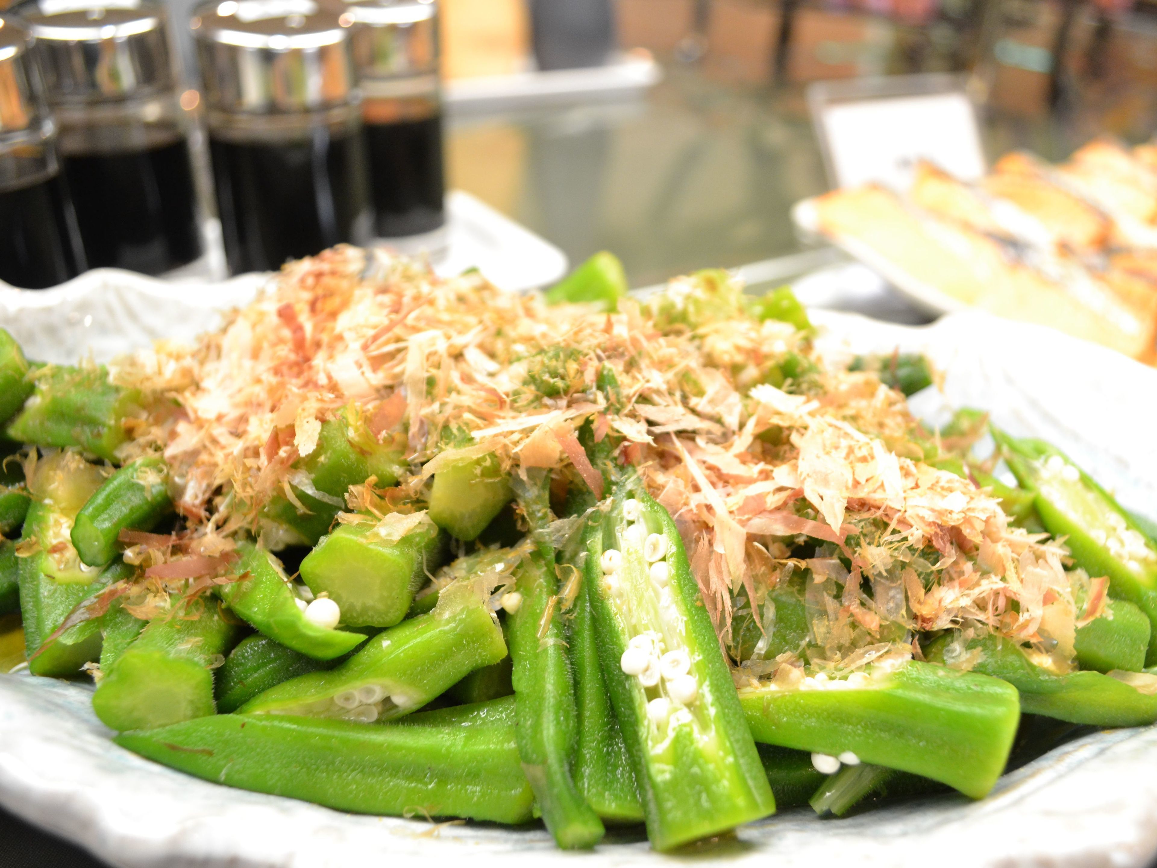 A plate of okra topped with shredded cheese and bonito flakes.