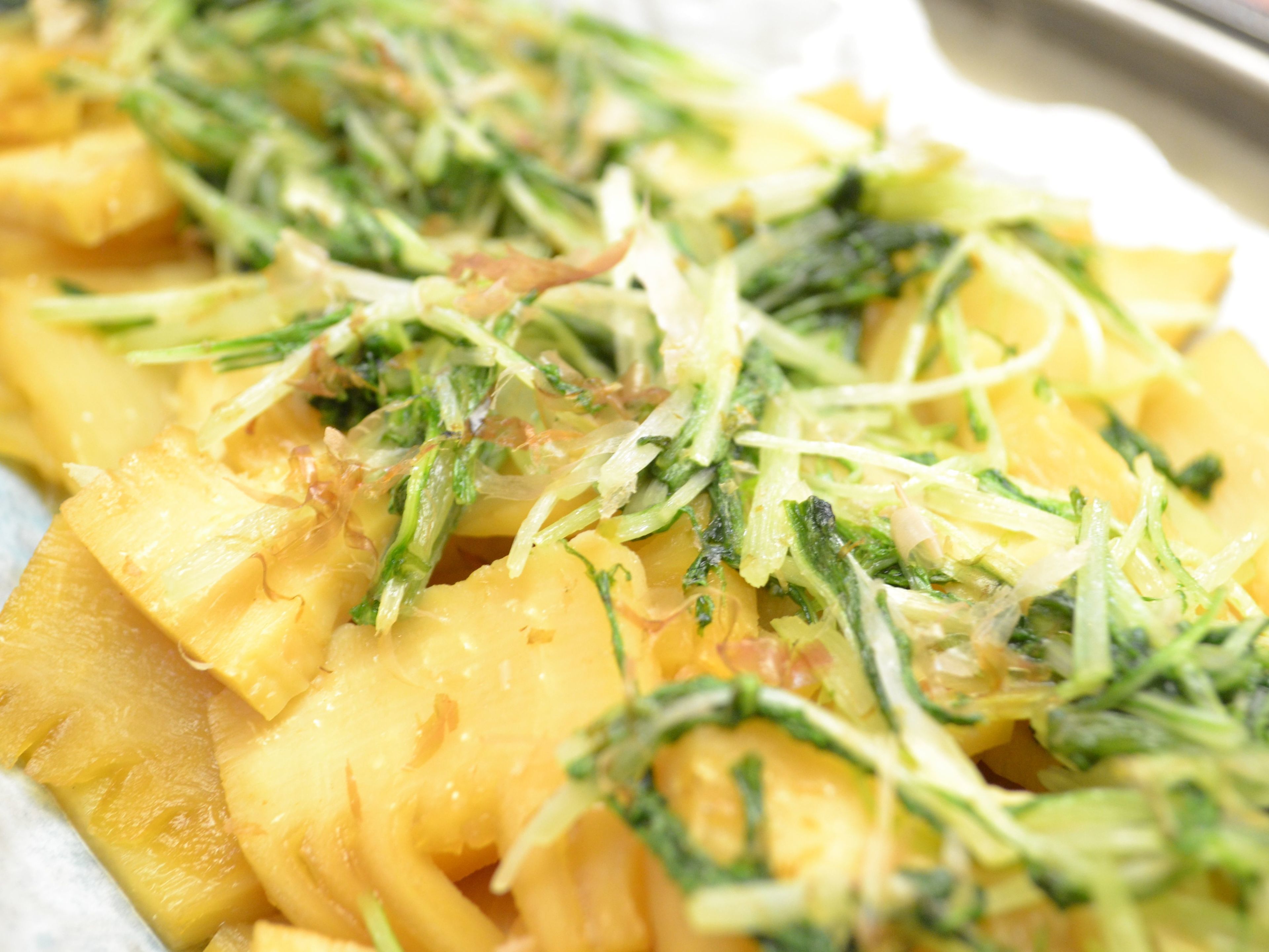A close-up of a dish with pineapple chunks and shredded green vegetables.