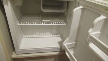 An empty white refrigerator with a shelf and a small compartment.