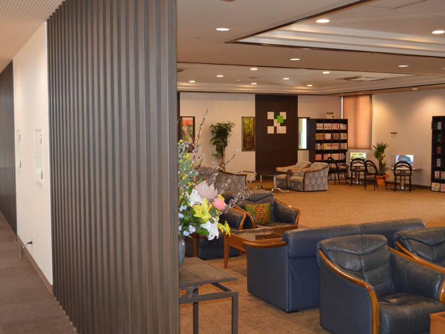 A spacious lobby with seating areas, a reception desk, and a bookshelf.
