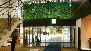 A hotel entrance with a glass door, a staircase to the left, and a green wall above. - Harazuru Grand Sky Hotel (Asakura)