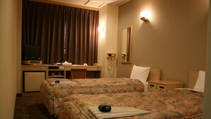 Een hotelkamer met twee bedden, een bureau met een computer, een telefoon en een televisie.