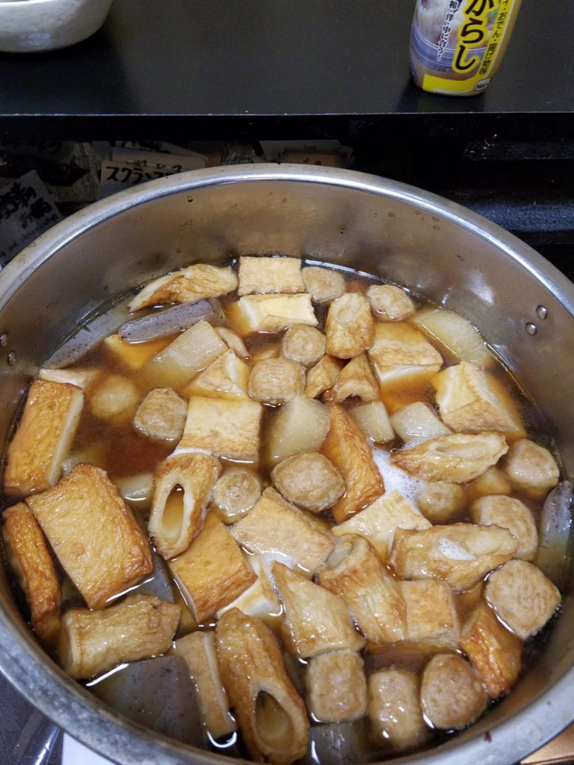 Una olla con diversos ingredientes, posiblemente para cocinar, y una botella de salsa de soja al fondo.