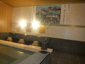 A traditional Japanese-style bathroom with a wooden floor, a long bench, and a large mirror. - Hotel Crown Hills Matsuyama (Matsuyama)