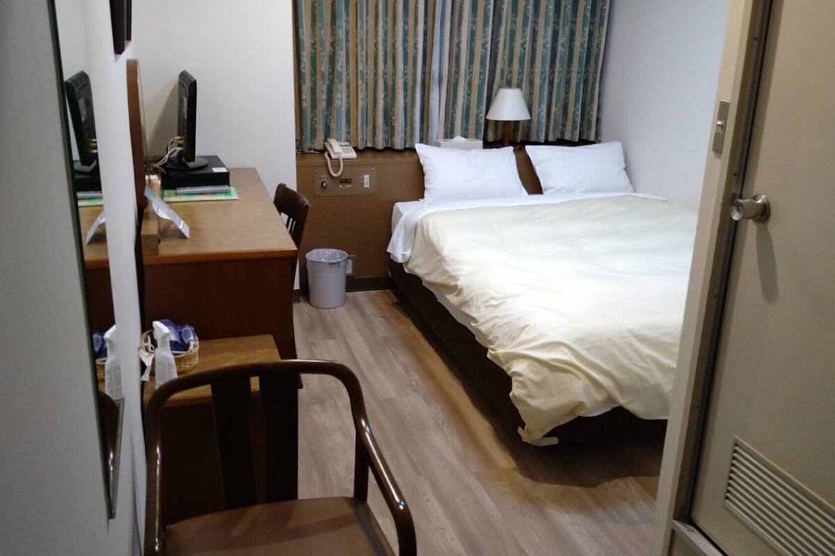 Ein Hotelzimmer mit Bett, Schreibtisch, Stuhl und Telefon.