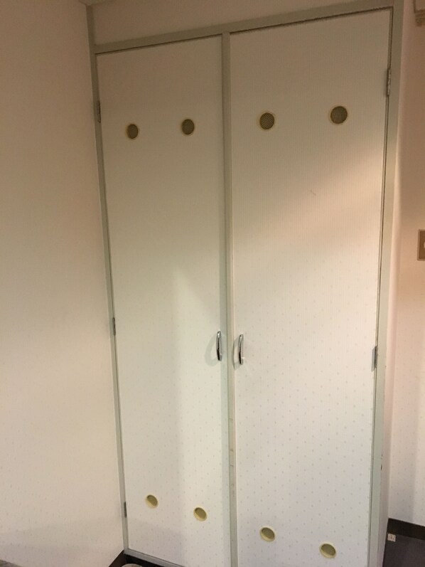 A white wardrobe with two doors, each featuring a circular vent and a handle. - Hotel Crown Hills Matsuyama (Matsuyama)
