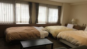 A hotel room with two beds, a small table, and a sofa.