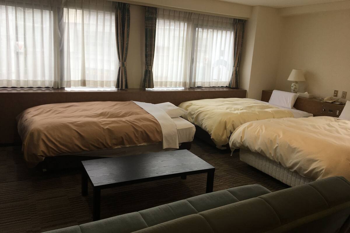 Ein Hotelzimmer mit zwei Betten, einem kleinen Tisch und einem Schlafsofa.