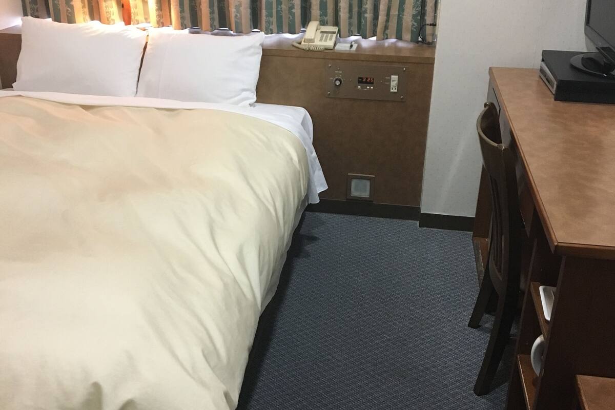 Ein Hotelzimmer mit einem Bett, einem Schreibtisch, einem Telefon und einem Fernseher.