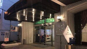 A hotel entrance with a glass door, a sign indicating a parking area, and a fire extinguisher mounted on the wall.