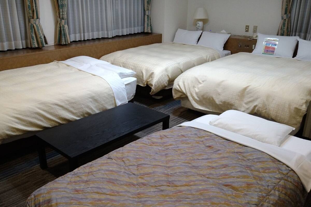 Ein Hotelzimmer mit zwei Betten, einer Bank und einem Nachttisch mit Lampe.