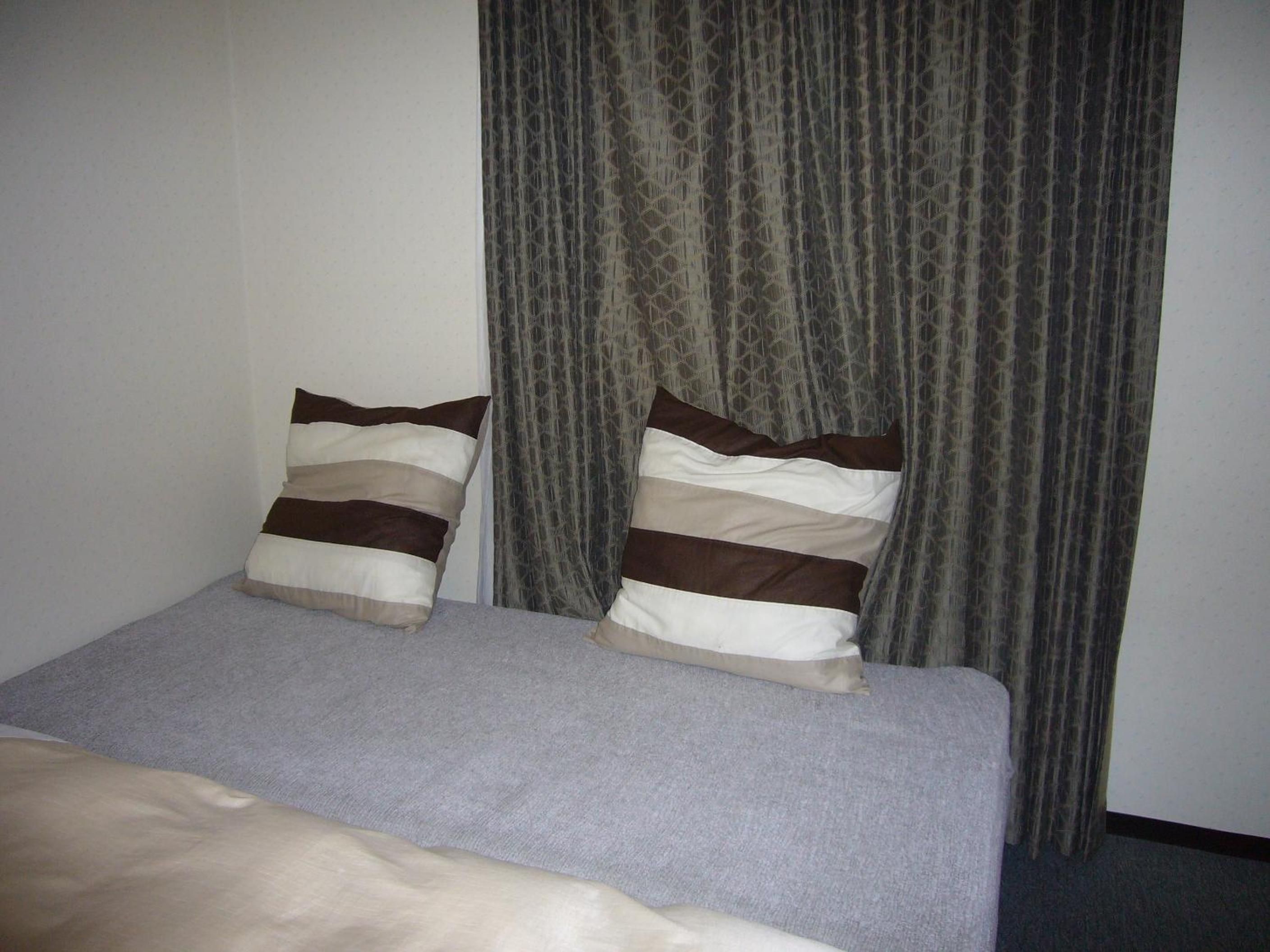A bed with two pillows and a grey blanket.