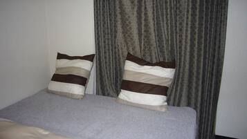A bed with two pillows and a grey blanket.