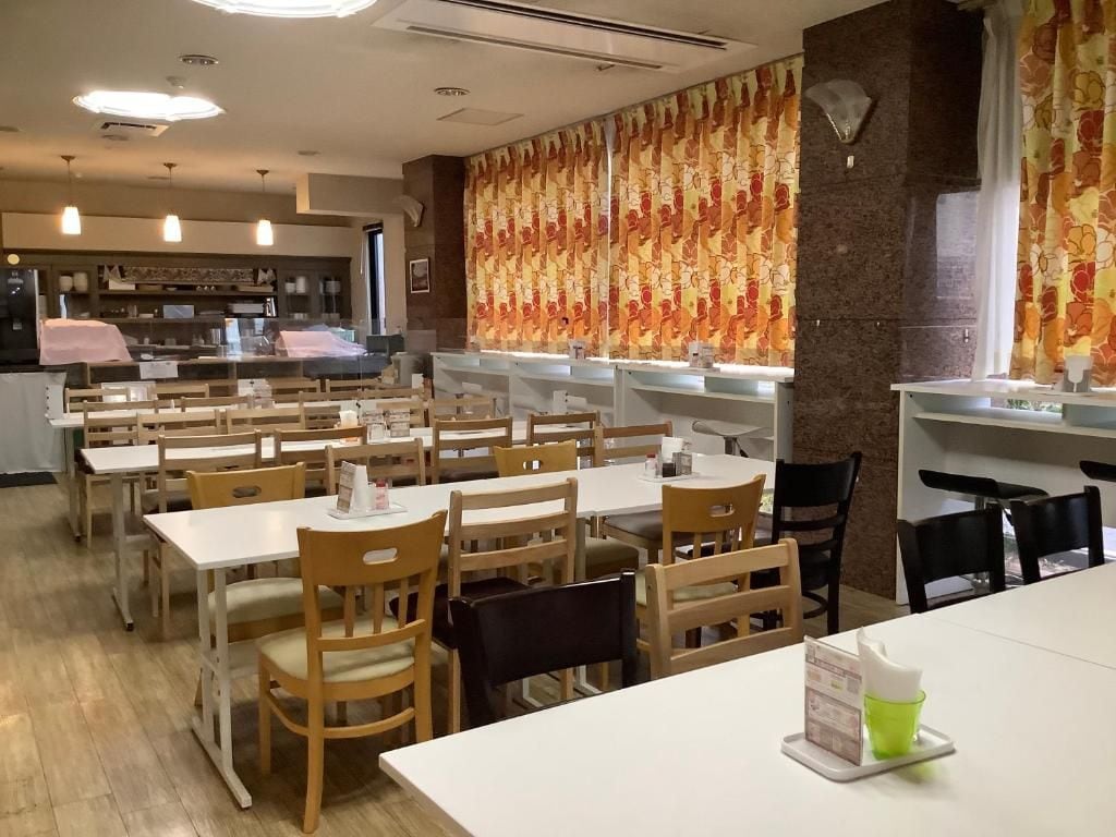 Een restaurant met meerdere tafels en stoelen, een toonbank met een menukaart, en een behangen muur.