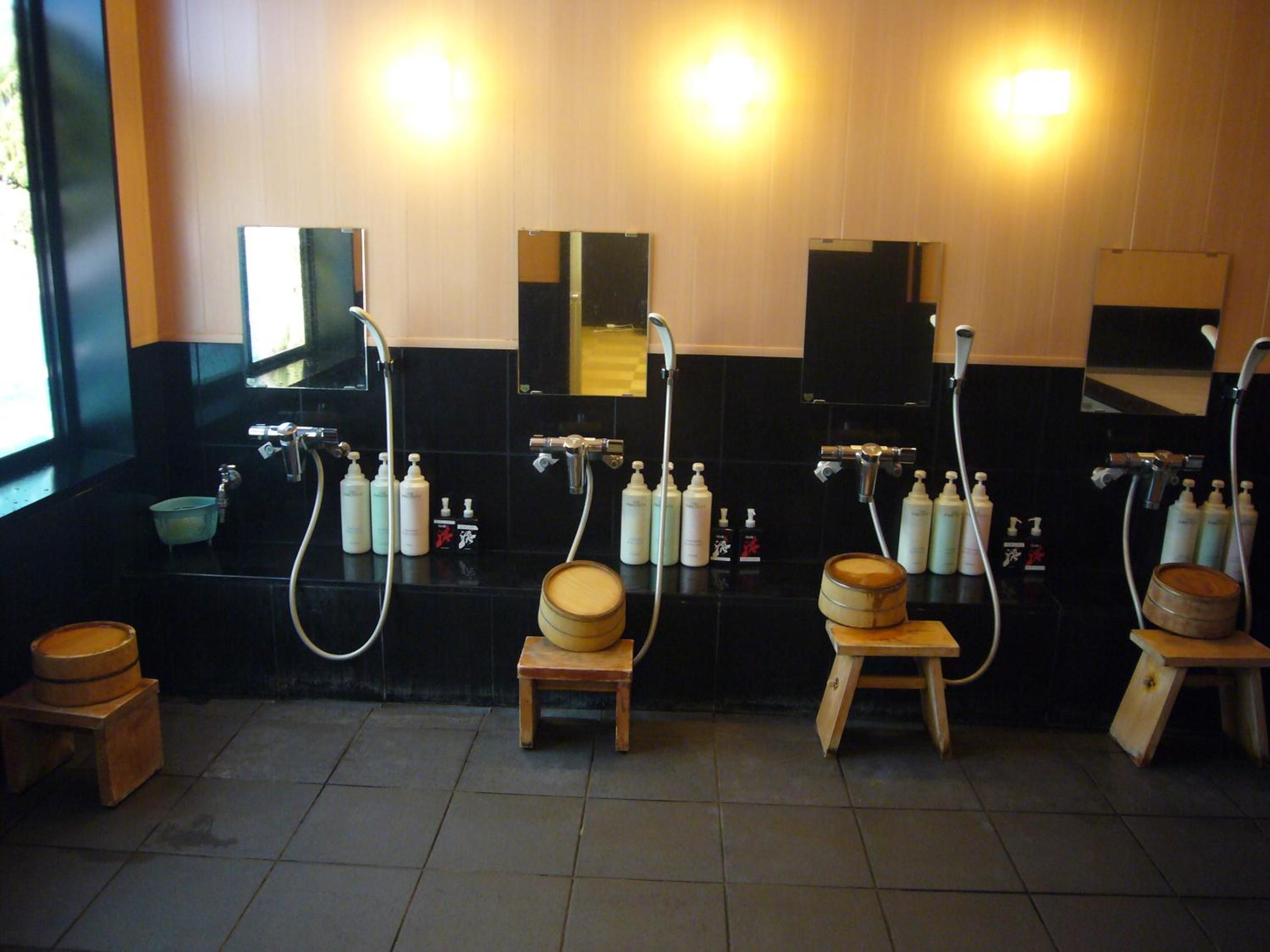 A public restroom with multiple sinks, mirrors, and wooden stools.