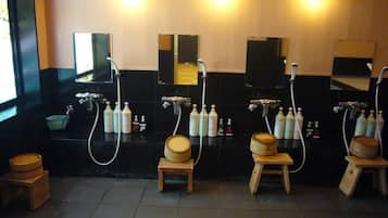 Baño público con varios lavamanos, espejos y taburetes de madera.