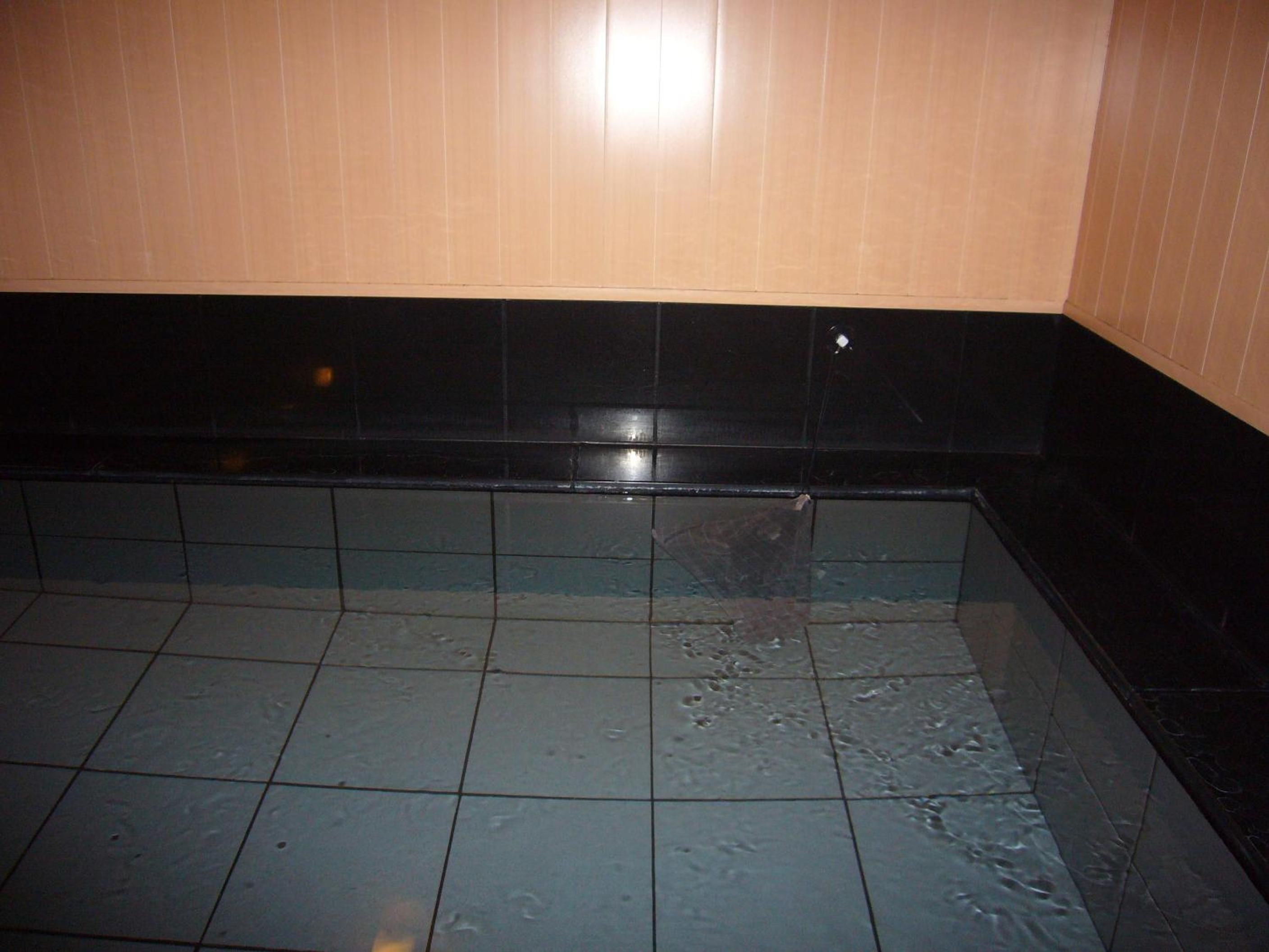 A tiled floor with a black border and a wooden panel wall.