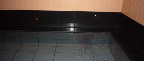 A tiled floor with a black border and a wooden panel wall.