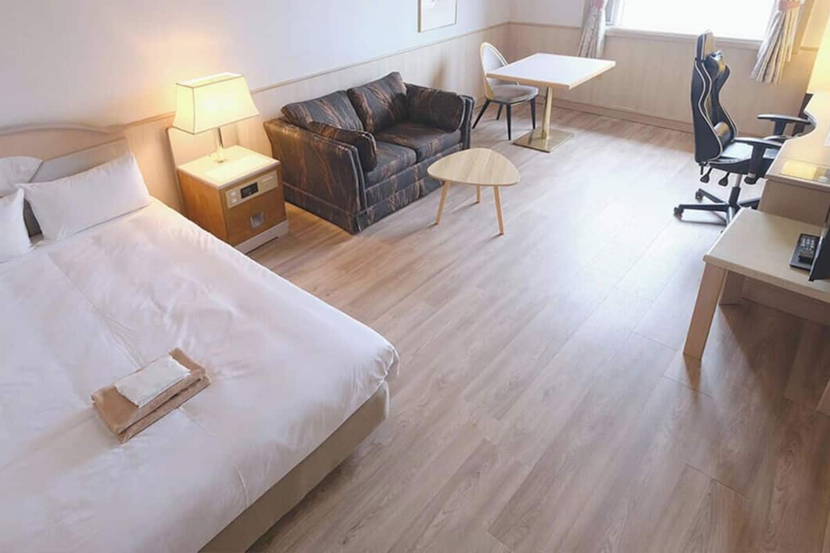 Una habitación de hotel con una cama grande, un sofá, un escritorio y una silla.