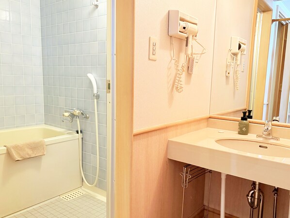 A bathroom with a bathtub, a shower, a sink, and a hairdryer mounted on the wall.